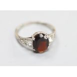 An 18ct, plat and oval garnet set dress ring with diamond set shoulders, size O, gross 2.7 grams.