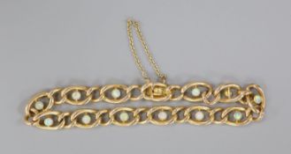 An early 20th century yellow metal and twelve stone white opal set oval link bracelet, 19cm, gross