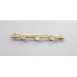 A yellow metal and three stone diamond set bar brooch, 58mm, gross 4.9 grams, set with one oval