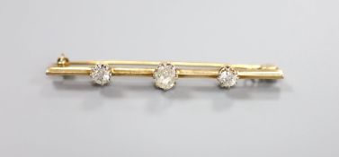 A yellow metal and three stone diamond set bar brooch, 58mm, gross 4.9 grams, set with one oval