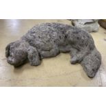 A reconstituted stone garden ornament of a sleeping spaniel, length 50cm