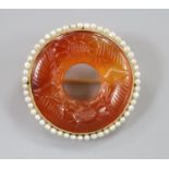 An early 20th century yellow metal(stamped 14), carved carnelian and seed pearl set openwork
