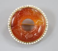 An early 20th century yellow metal(stamped 14), carved carnelian and seed pearl set openwork