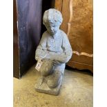 A reconstituted stone garden ornament of a boy reading, height 50cm