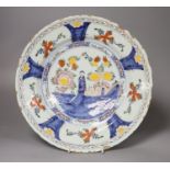 A large polychrome Delft charger, painted with a central figure beside a walled garden, set within