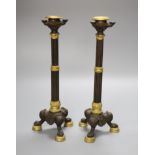 A pair of 19th century French bronze and ormolu mounted candlesticks with fluted stems, on tripod