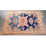 A Kerman Lavar rug, the blue field woven with pink stylised floral medallions, within a shaped