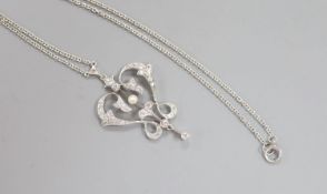 An Art Nouveau style white metal seed pearl and diamond set openwork scroll drop pendant necklace,