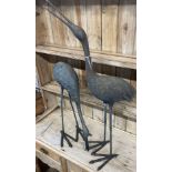 A pair of patinated cast metal garden cranes, larger 91cm high