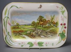 A rectangular dish with rounded corners painted with painted with sheep, a man and dog and a country