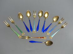 Six Norwegian sterling gilt and enamel small forks and six sterling and blue enamel coffee spoons.