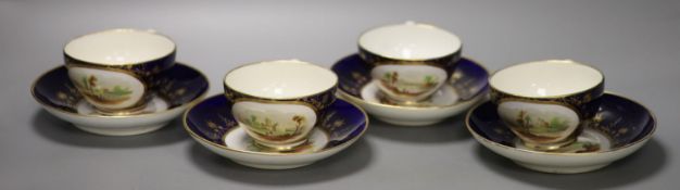 A set of four Derby cups and saucers painted with landscapes on a cobalt blue ground by Henry Lark