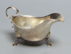 A silver sauce boat, having shaped edge, flying scroll handle and three hoof feet, marks rubbed,