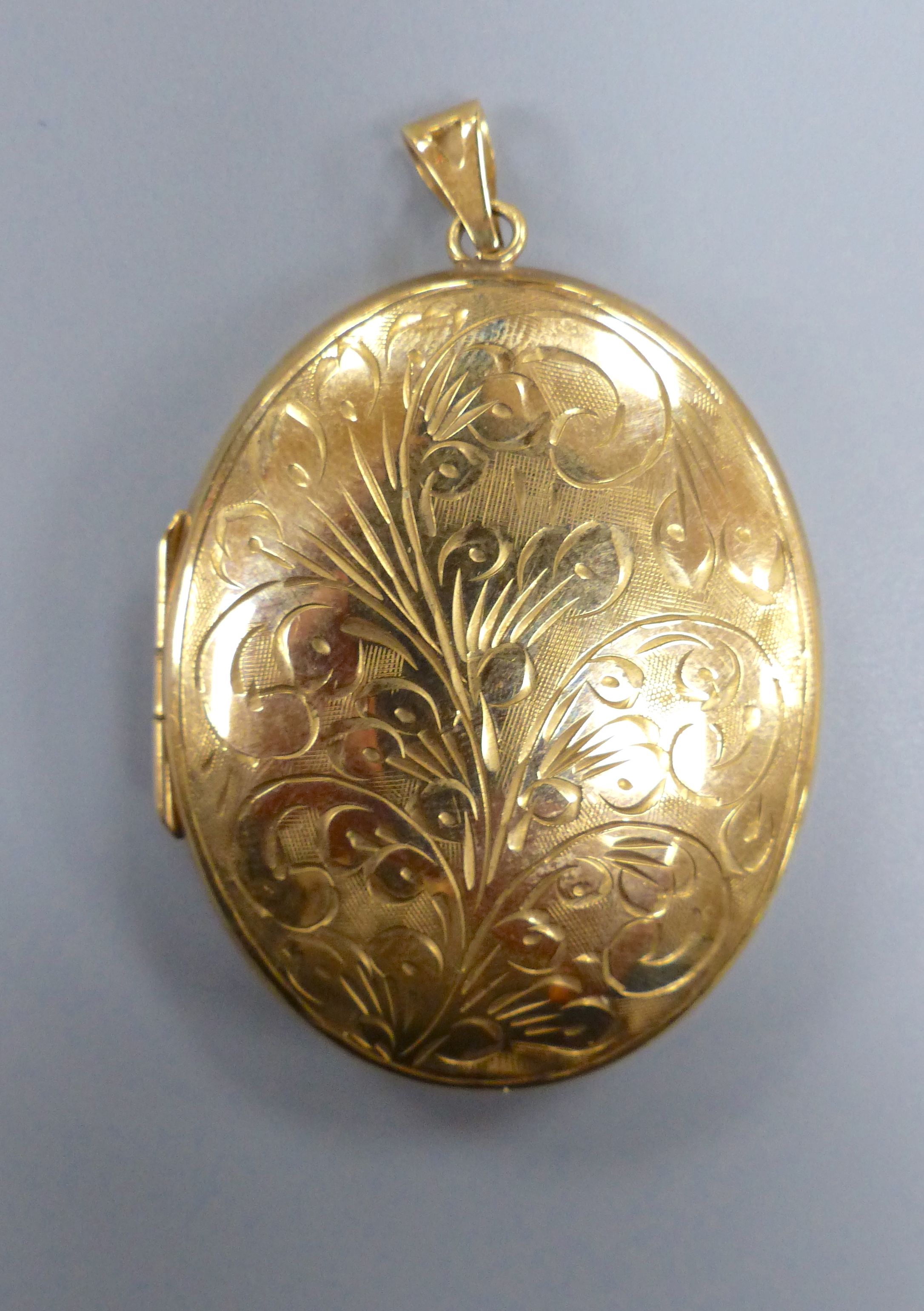 A modern engraved 9ct gold oval locket, 47mm, gross 18.6 grams.