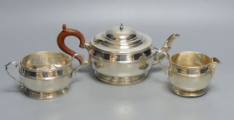 A matched silver three-piece tea service of squat reeded circular form, comprising teapot, milk