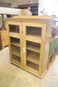 A modern glazed pine bookcase fitted two doors and shelves, length 114cm, depth 34cm, height 140cm