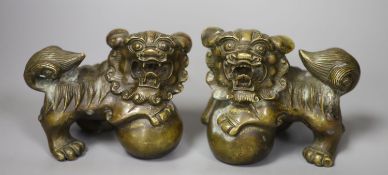 A pair of 20th century cast metal Chinese temple lions (filled). 11cm. long, 11cm. high.