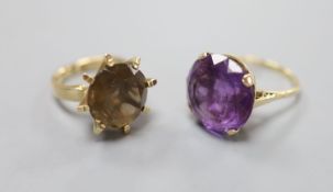 A modern yellow metal and amethyst dress ring and a similar smoky quartz ring, gross 15.2 grams.