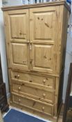 A contemporary pale pine press cupboard with twin panelled cupboard doors over a base fitted with