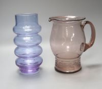 An Art glass pale amethyst jug with ribbed foot and a pale blue glass cylindrical ring-form vase,