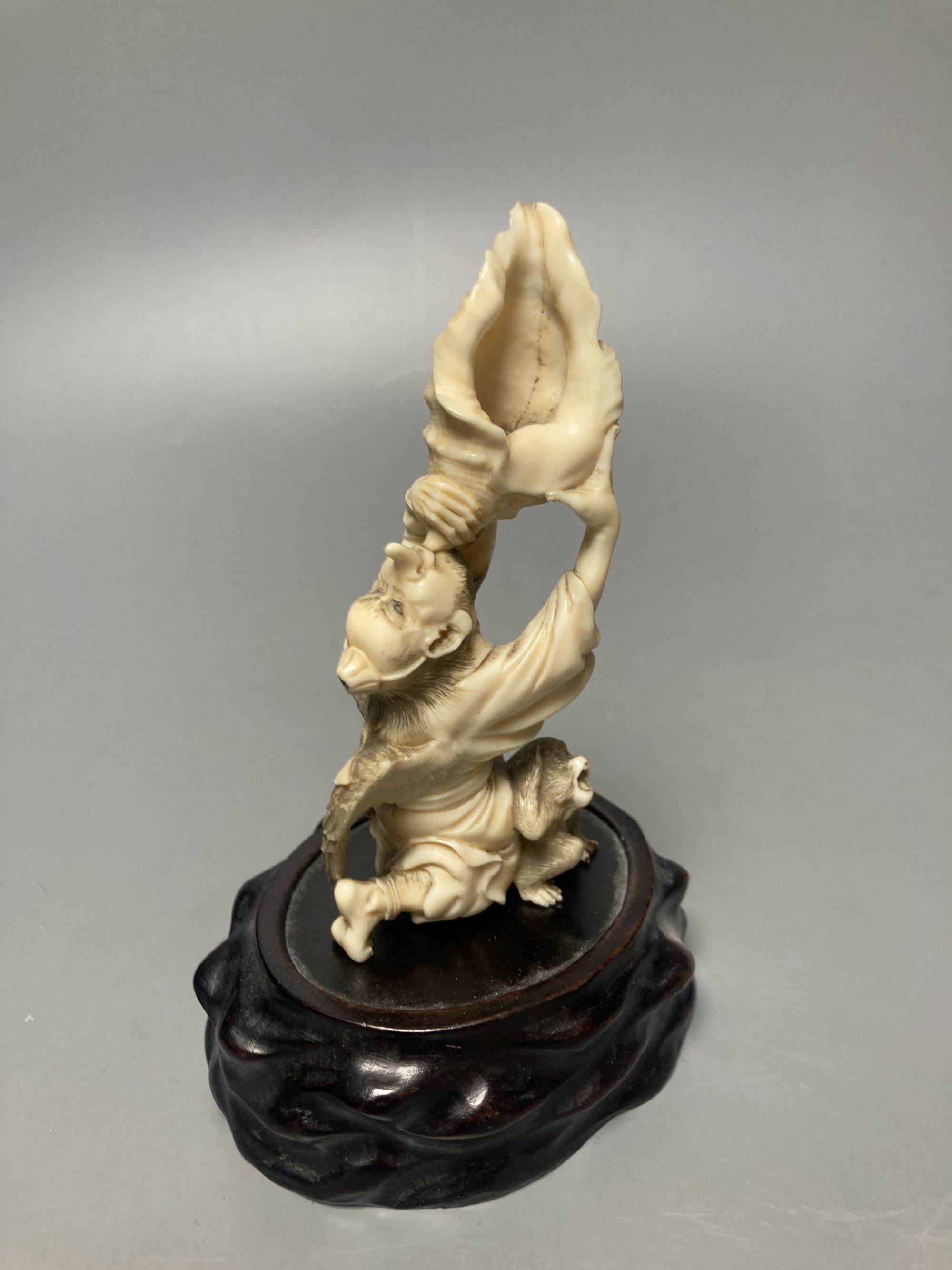 A Japanese ivory okimono of a winged man blowing a conch, monkey below, Meiji - Image 2 of 4