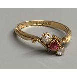 An Edwardian 18ct gold, red spinel and diamond set three stone crossover ring, size O, gross 2.9
