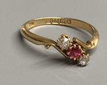 An Edwardian 18ct gold, red spinel and diamond set three stone crossover ring, size O, gross 2.9