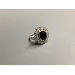 A modern 18ct white gold, sapphire and diamond set oval cluster ring, size L/M, gross weight 7.5