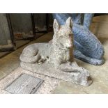 A reconstituted stone garden ornament of a recumbent German Shepherd dog, length 50cm