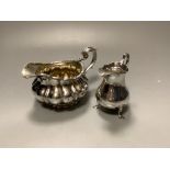 A George III silver baluster cream jug and a George IV silver cream jugof circular fluted form (2),