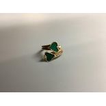 A modern yellow metal, two stone heart shaped malachite and two stone diamond set crossover ring,