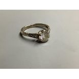 An 18ct, white metal and single stone diamond ring, with diamonds set shoulders, size M, gross