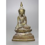 A small 19th century or later Tibetan lacquered cast brass figure of a seated Buddha, (filled), 18cm