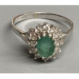A modern 18ct white gold, emerald and diamond set oval cluster ring, size O/P, gross 3.6 grams.