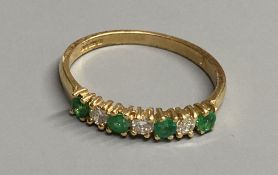 A modern 18ct gold, four stone emerald and three stone diamond set half hoop ring, size M/N, gross