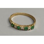 A modern 18ct gold, four stone emerald and three stone diamond set half hoop ring, size M/N, gross