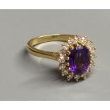 A modern 18ct gold, amethyst and diamond set oval cluster ring, size N, gross 4.9 grams.