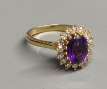 A modern 18ct gold, amethyst and diamond set oval cluster ring, size N, gross 4.9 grams.