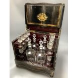 A French ebonised decanter case, c.1870, hinged lid opening to reveal four liqueur decanters and