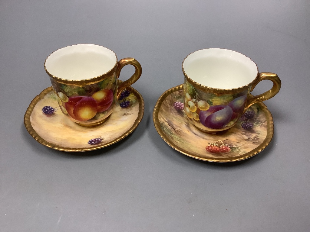 A pair of Royal Worcester fruit painted coffee cups and saucers, signed Freeman, (one saucer