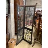 An early 20th century glazed oak two fold screen, each panel width 51cm, height 176cm