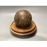 A 17 / 18th century canon ball, on hardwood stand