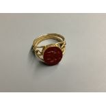 A yellow metal and carved oval Jasper set signet ring, with pierced shank, the matrix carved with