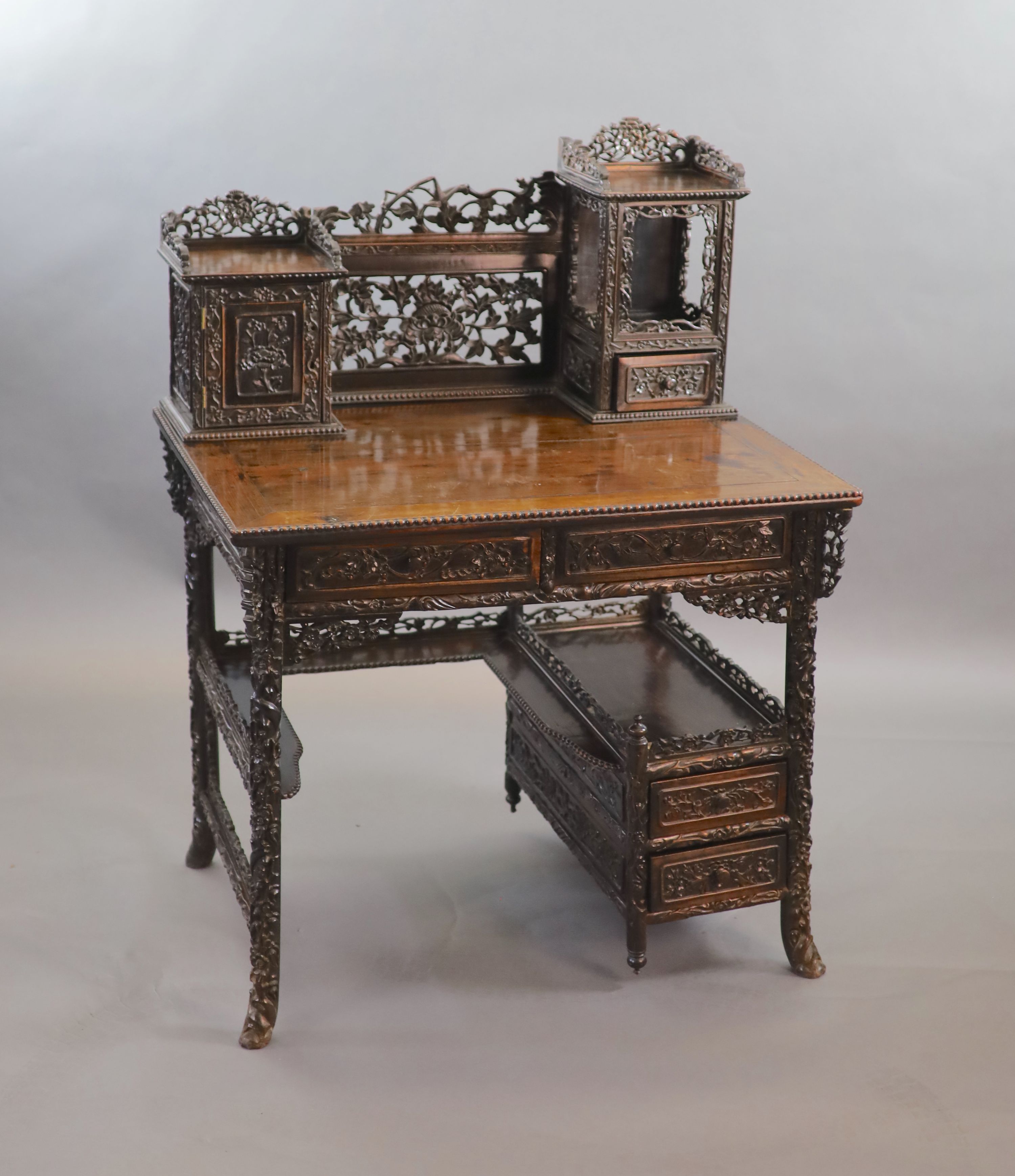 A late 19th century Chinese hongmu desk,carved and pierced throughout with flowers, the raised