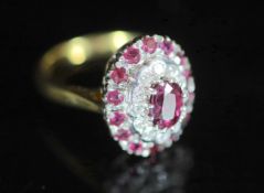 A modern 18ct gold, ruby and diamond set oval cluster ring,with central oval cut ruby, bordered