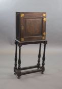 An early 18th century European japanned cabinet on stand,the single panelled door with gilt brass