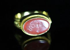 A Venetian 22ct gold and antique oval carnelian set signet ring,carved with a serpent and bird,