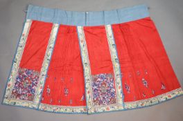 A 19th century Chinese red ground silk skirt,embroidered with blue flowers and auspicious symbols