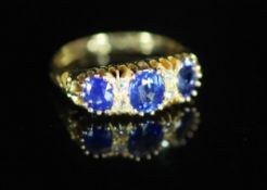 An Edwardian 18ct gold and three stone sapphire set half hoop ring with diamond chip spacers,with