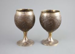 A pair of George III silver mounted coconut cups by Phipps & Robinsoncarved with rams head crests